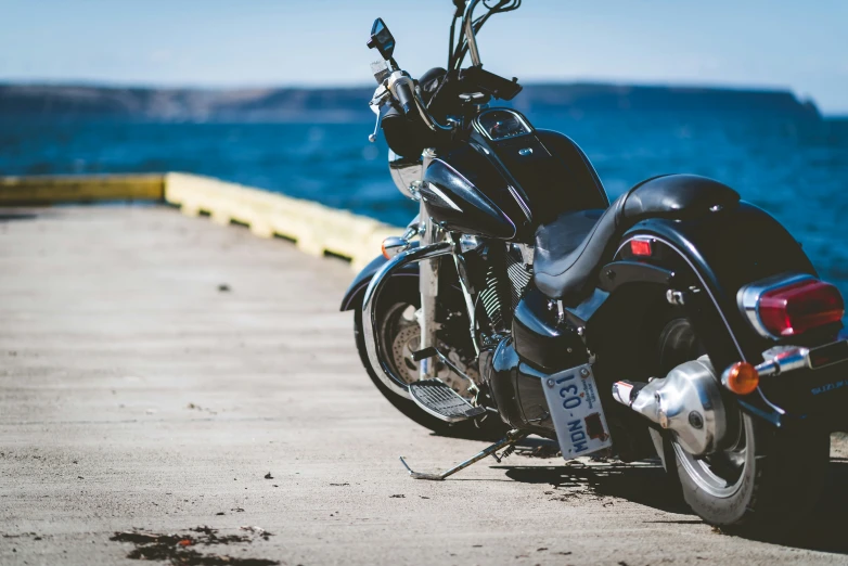 a black motorcycle parked next to the ocean