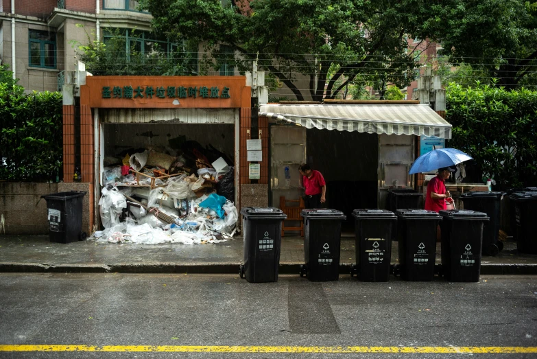 a woman and a boy stand by trash on a street corner