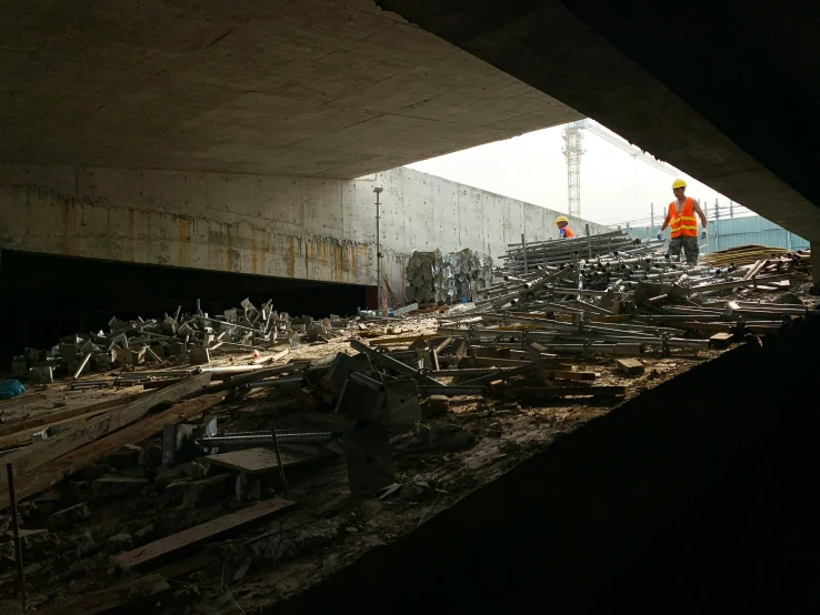 workers stand on a construction site beside a bridge