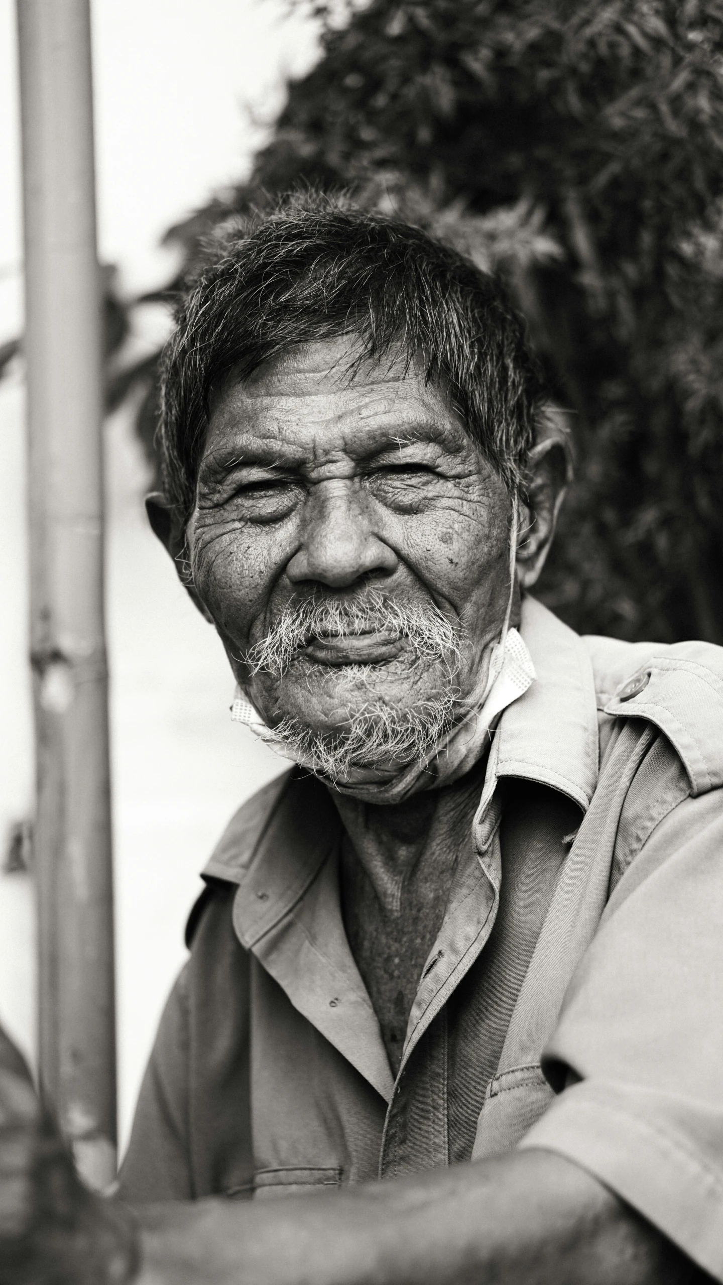 black and white pograph of man sitting by tree