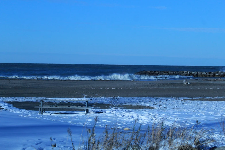 snow covered field with ocean and large stone wall