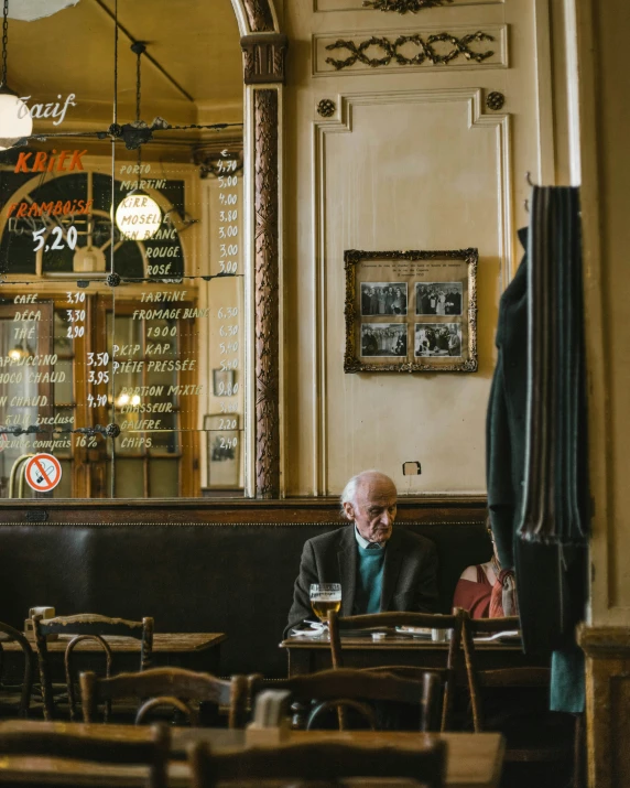 man sits alone in an old - fashioned restaurant looking at his phone