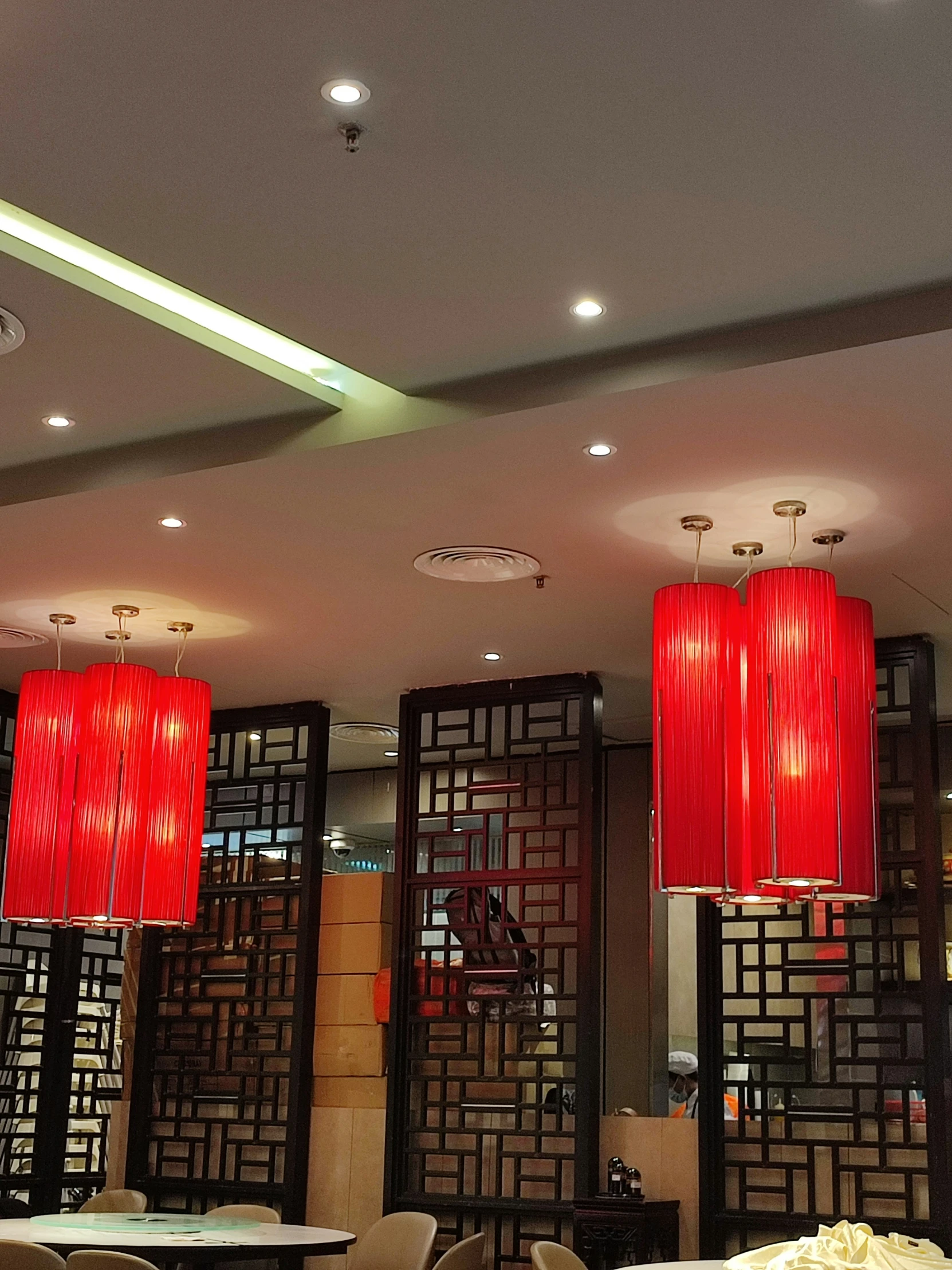 a room with tables, chairs and two red lamps on the ceiling