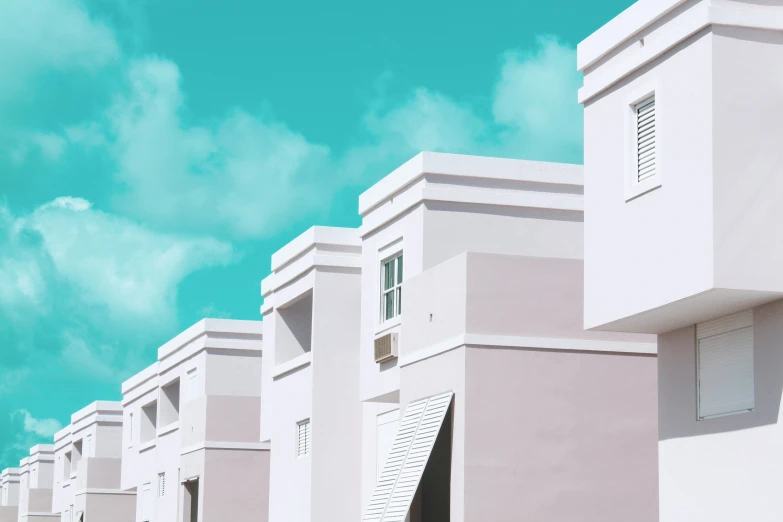 many gray buildings with closed windows under a bright blue sky