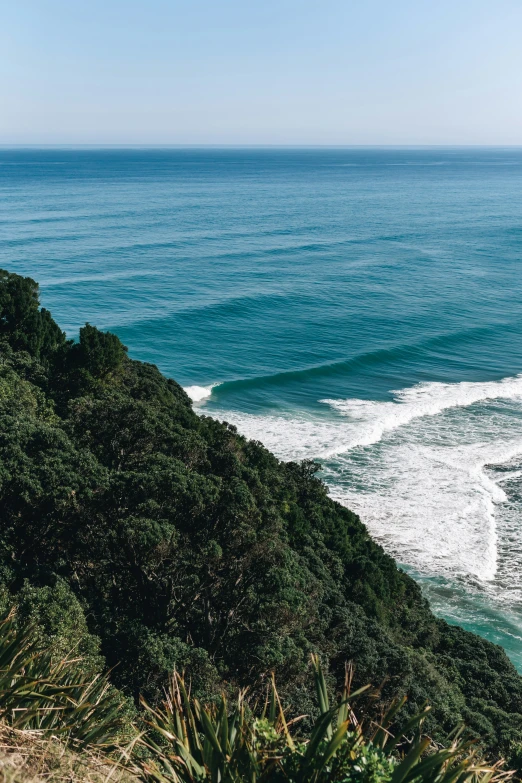 the blue water has a wave crashing into shore