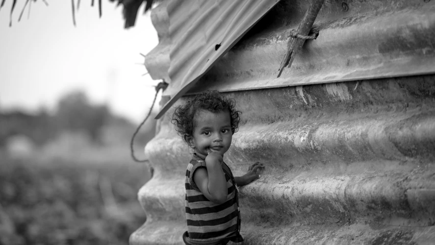 the child looks at soing while standing against a wall