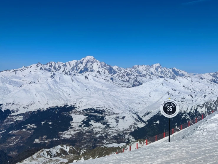 a snow covered mountain has a speed limit sign in front of it