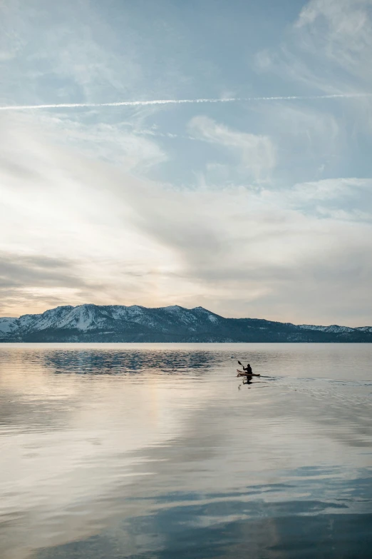 a small boat floating on top of a lake under a cloudy sky