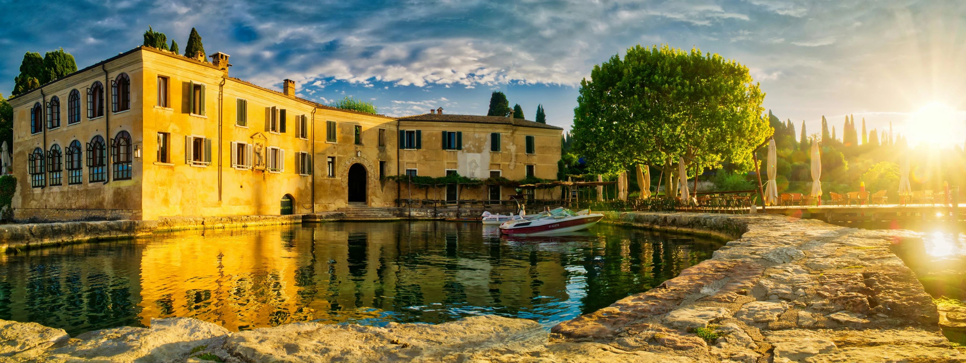 a sunbeam shines brightly from behind a yellow building over water