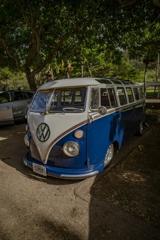 an old blue and white bus parked in the shade