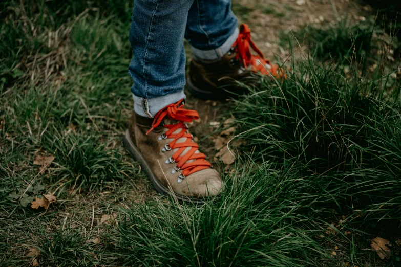 a person wearing red laces is standing on grass