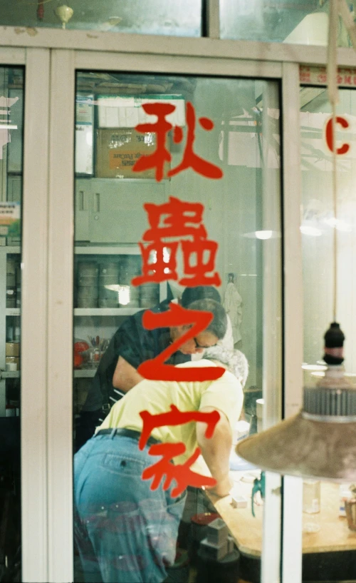 two people at a counter with red writing in the window