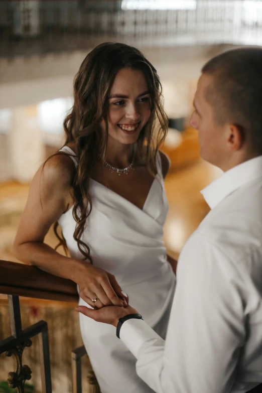 a man and woman in formal wear smile as they hold hands