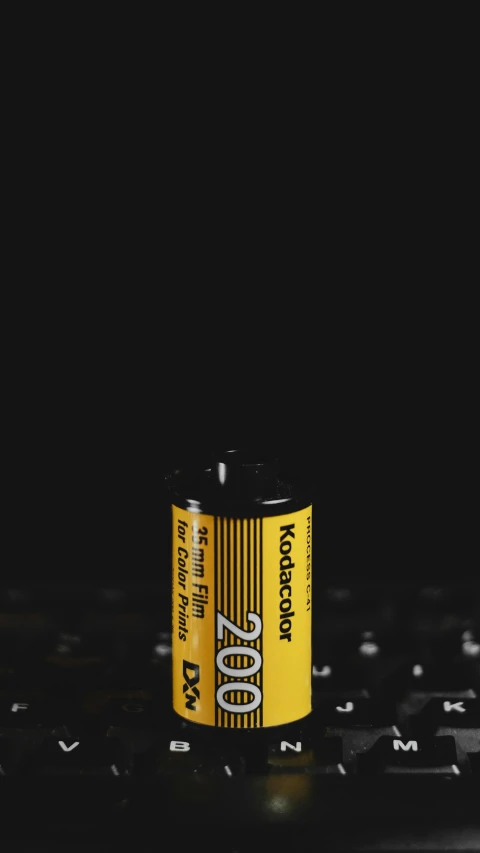 a flashlight laying on a computer keyboard and has a yellow battery