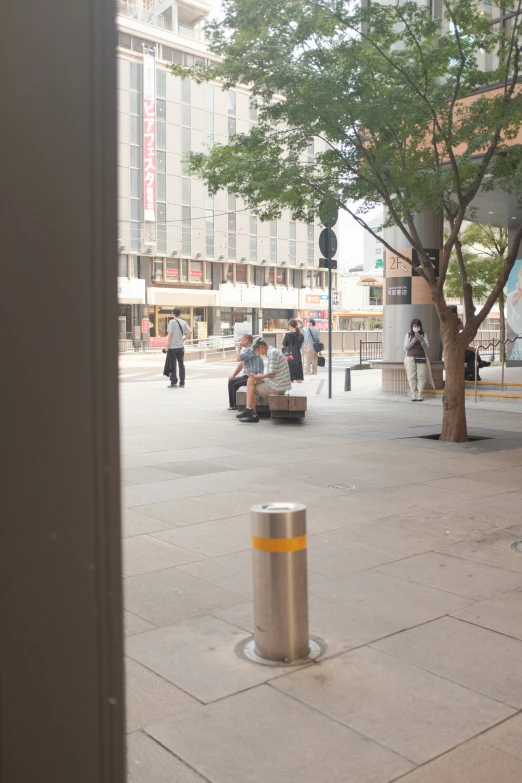 people sitting on benches on the sidewalk of a city street