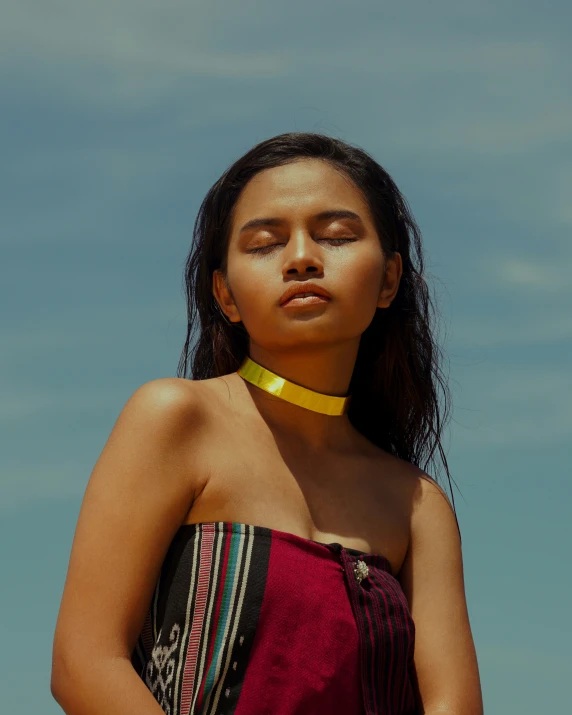 a young woman in a striped dress wearing a yellow necklace