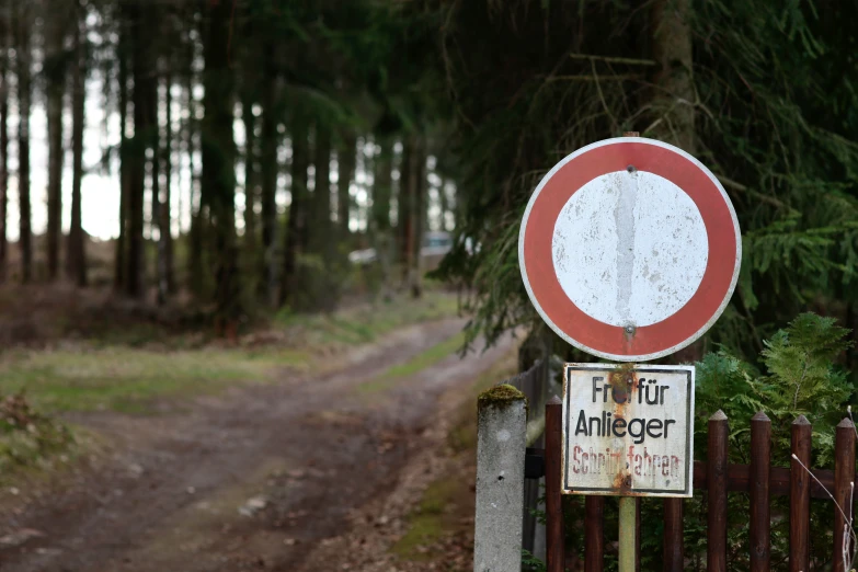 a red and white sign on a fence beside a road