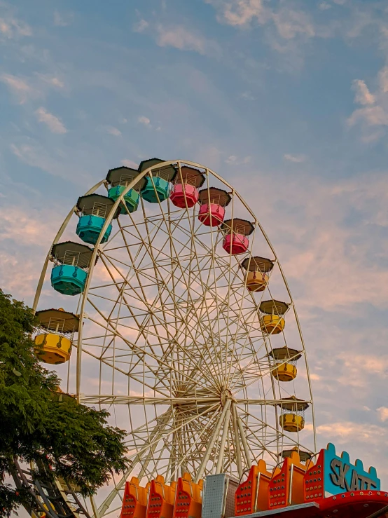 a ferris wheel in a cloudy sky with brightly colored chairs on it