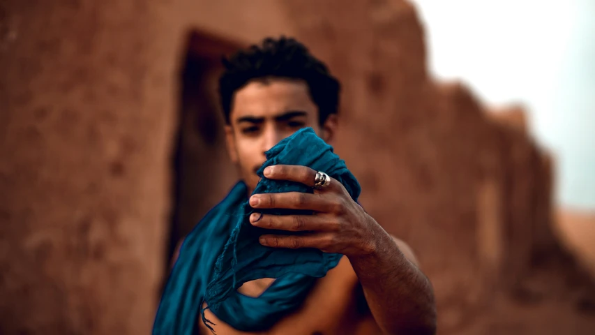 a man wearing an animal - themed ring stands in front of a building holding up his cell phone