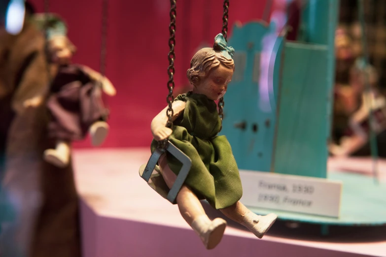 a doll is on a swing in a toy store