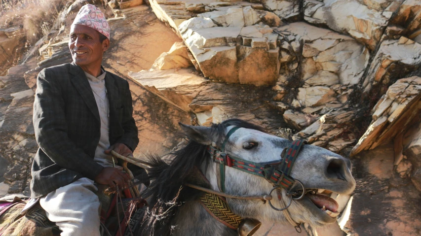a man on a horse with saddle on rocky terrain