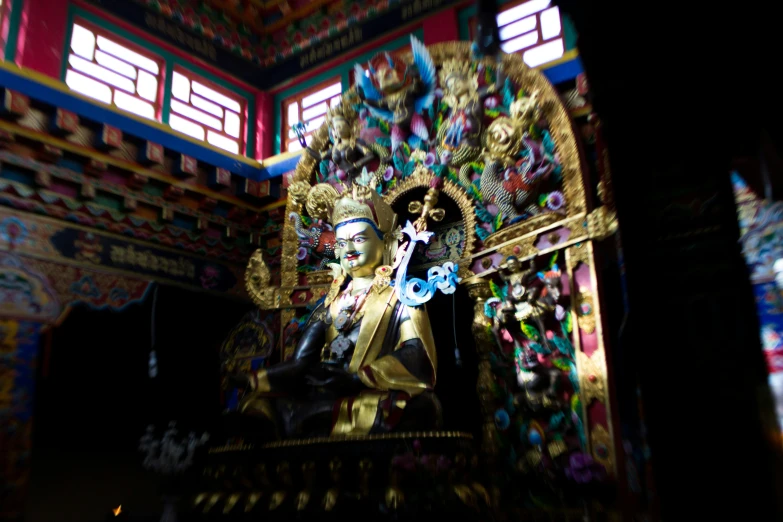 the statue of buddha under the brightly painted ceiling