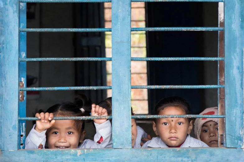 three little s looking out the window of an old building