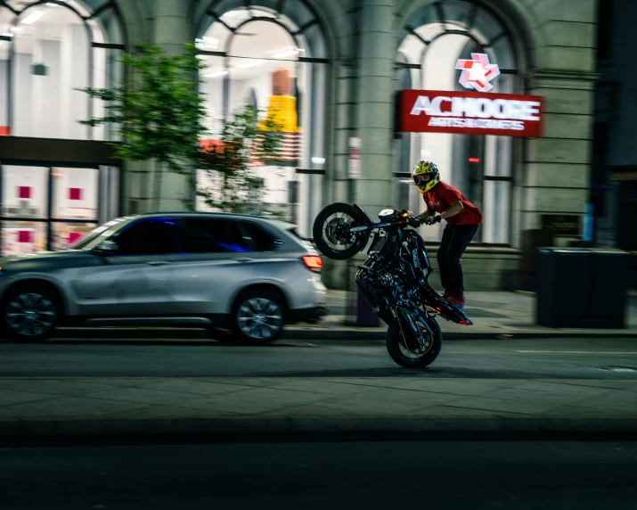 a man performing tricks on his bike in front of some cars