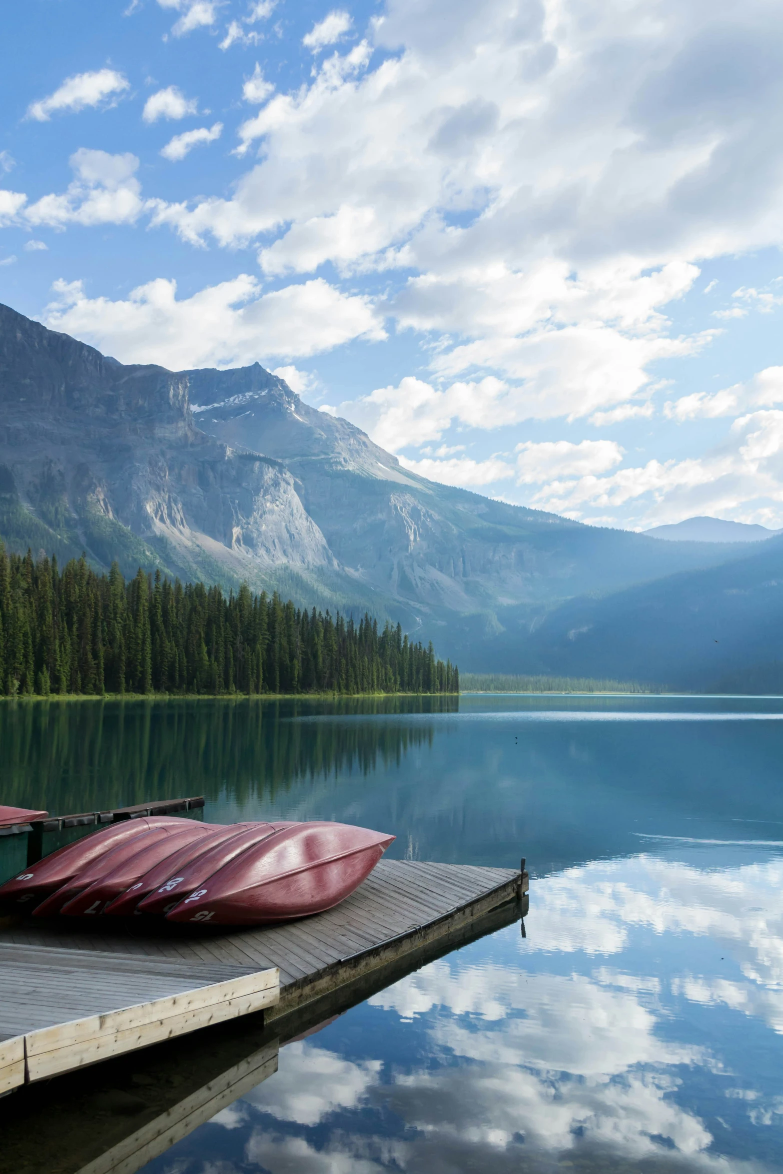 a rowboat and kayak on a dock overlooking a body of water with mountains in the background