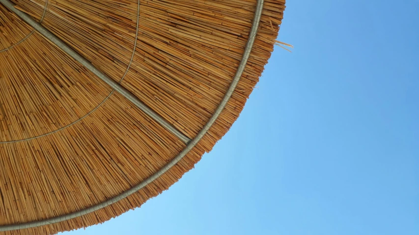 the roof of an umbrella with clear blue sky in background