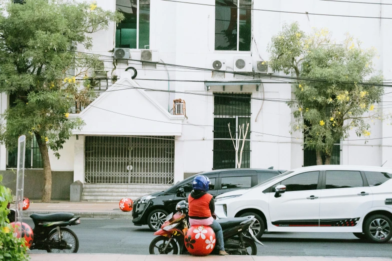 a street scene with people on motorcycles and parked cars