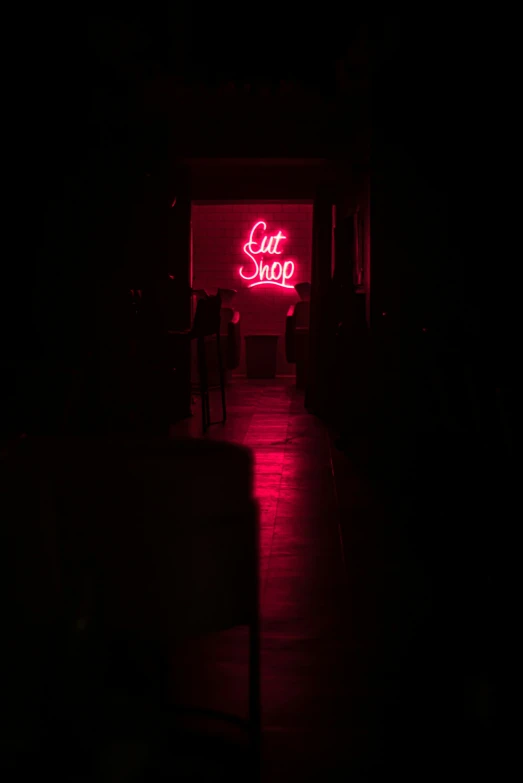 a red neon sign reads out shop and the lights are turned on