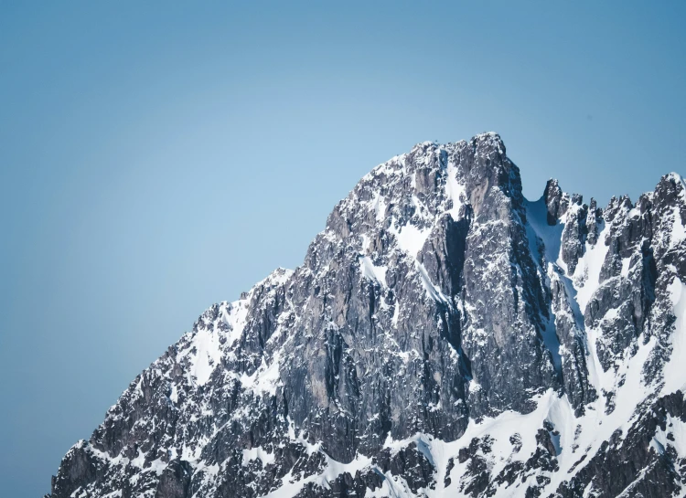 a snow covered mountain rises in the blue sky