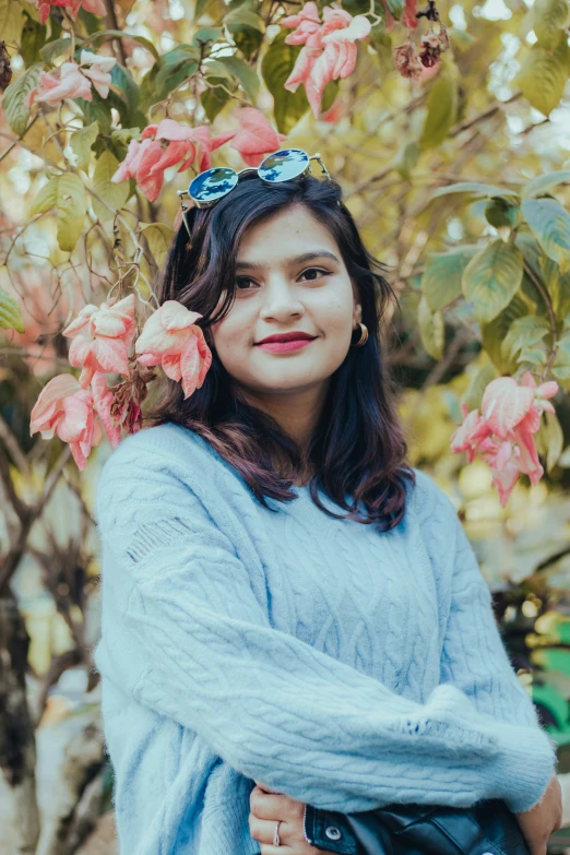 a woman stands by a flowering tree smiling