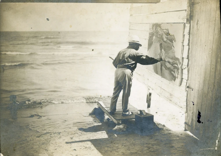 a man putting a painting on the wall next to the water