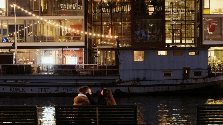 the people sit on the bench next to the river