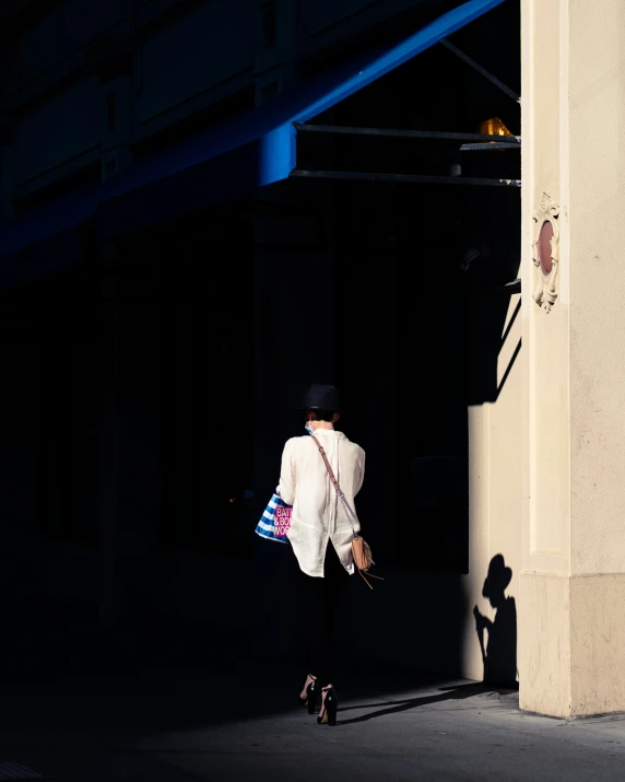 a woman walks down a street at night carrying a bag