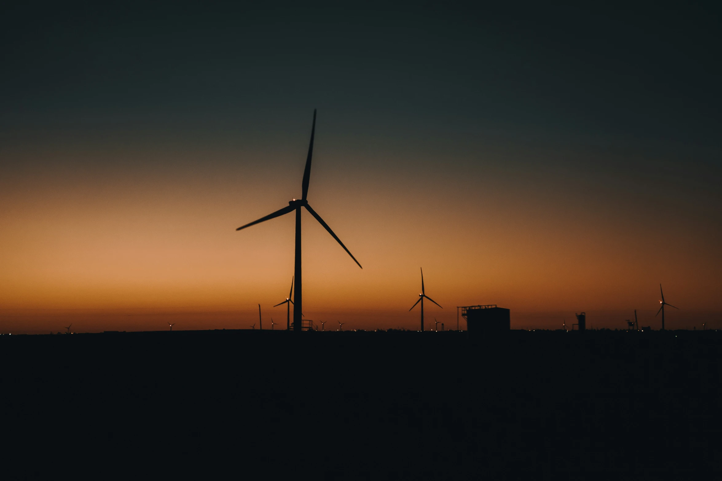 the silhouette of two windmills against the sunset