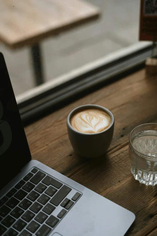 a laptop, glasses and glass of water on a wooden desk