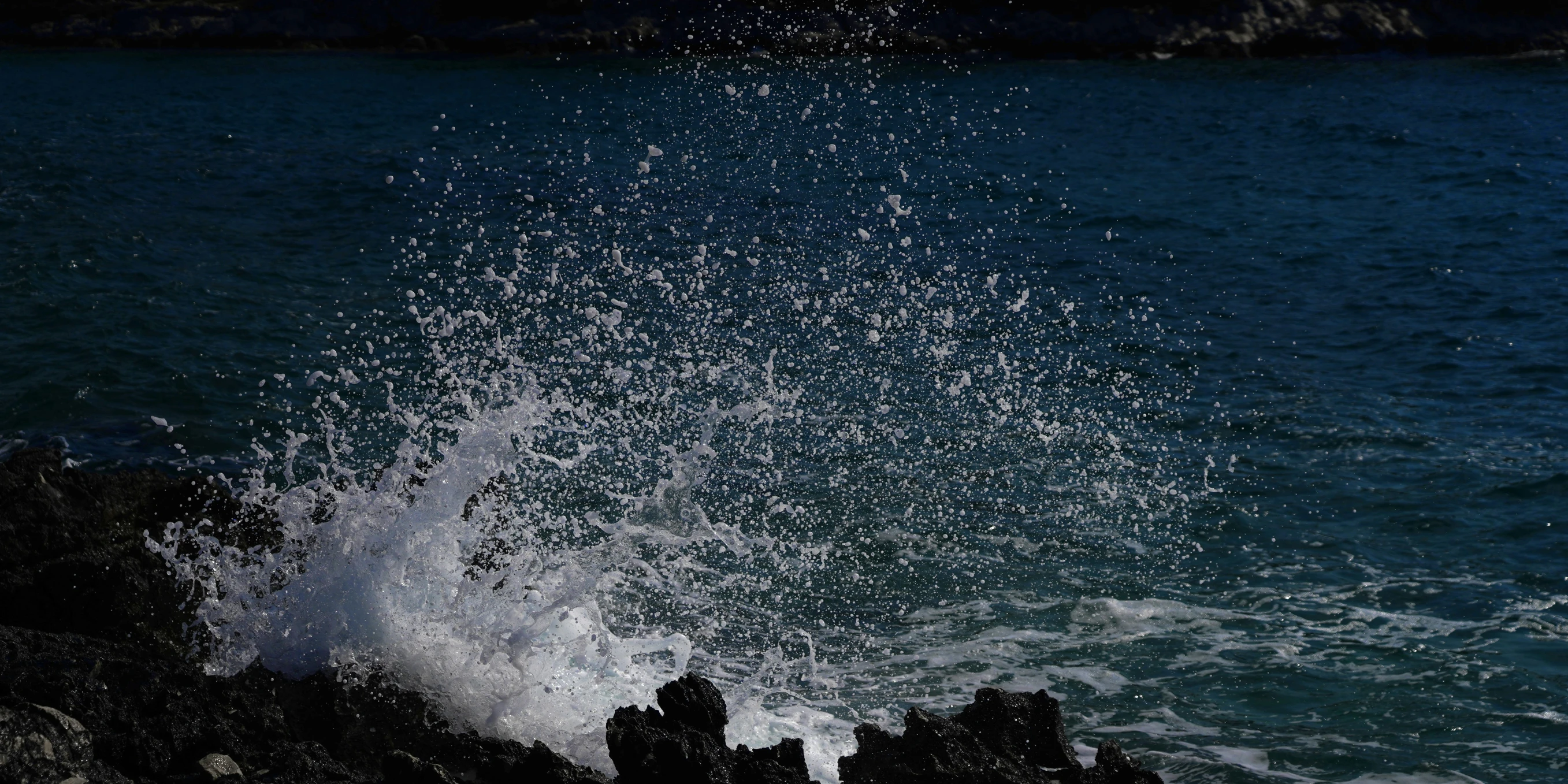 the water splashes against the rocky shore