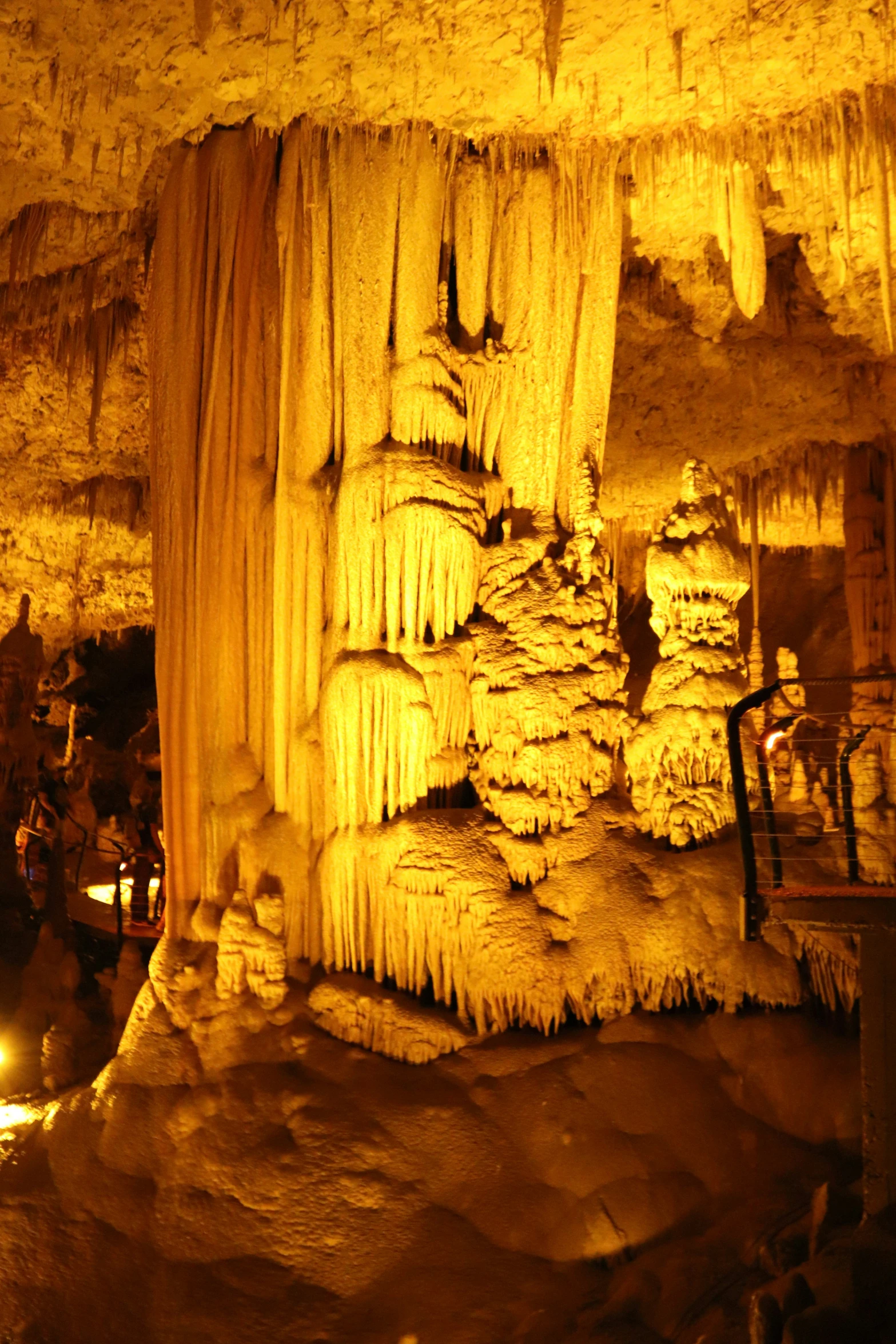 a cave with hanging icicles and people standing near them