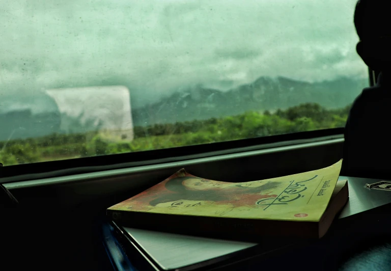 book sitting on the window sill next to mountains