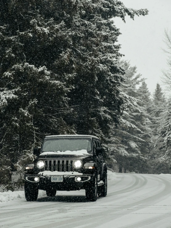 a black jeep drives down a snowy road