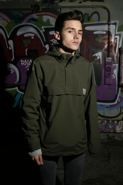 a man in an army green hoodie posing for the camera