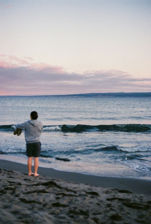 a man throwing a frisbee on the beach at dusk