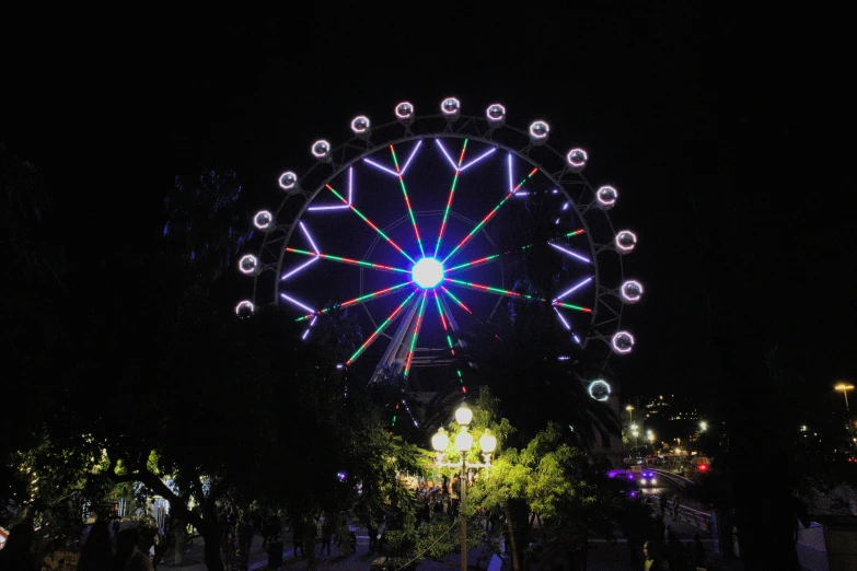 a big wheel is in the dark with a big crowd