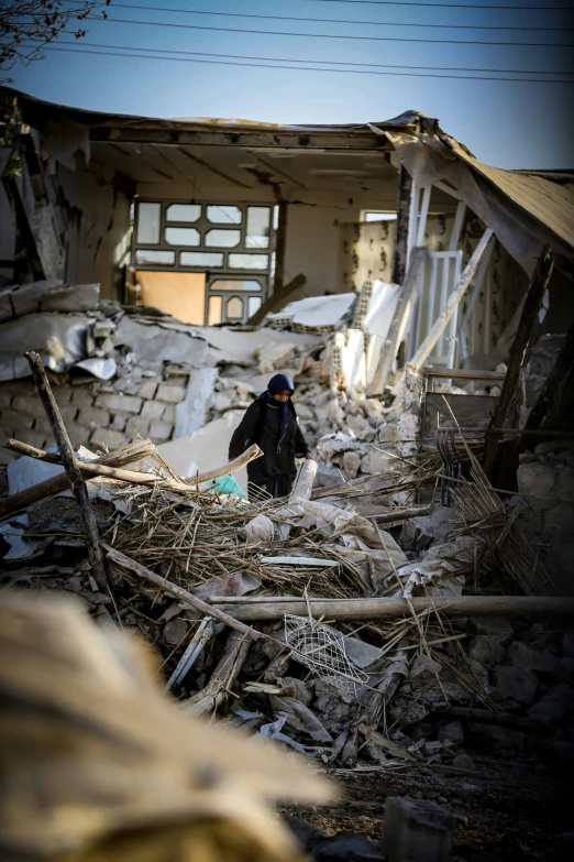 a man cleans debris from a destroyed house