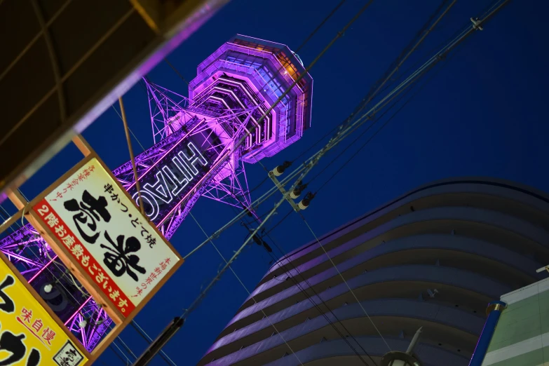 neon lights shine on a large tower next to buildings