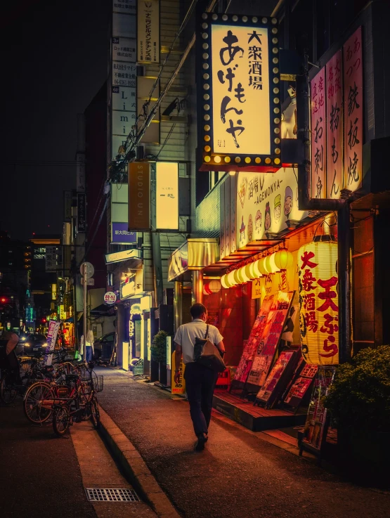 an asian man walking past several stores in the middle of the street