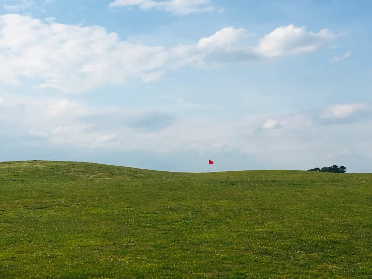 people fly kites on a hill side against blue sky